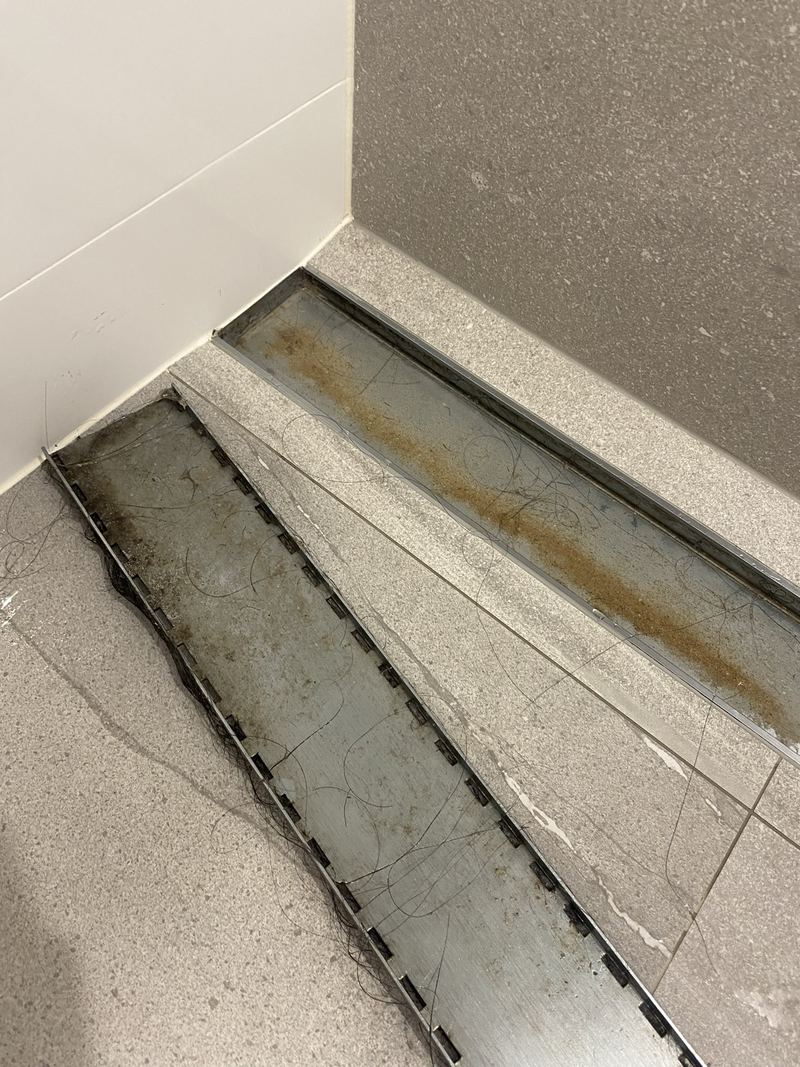 Shower drain channel with rust, hair and build-up before cleaning