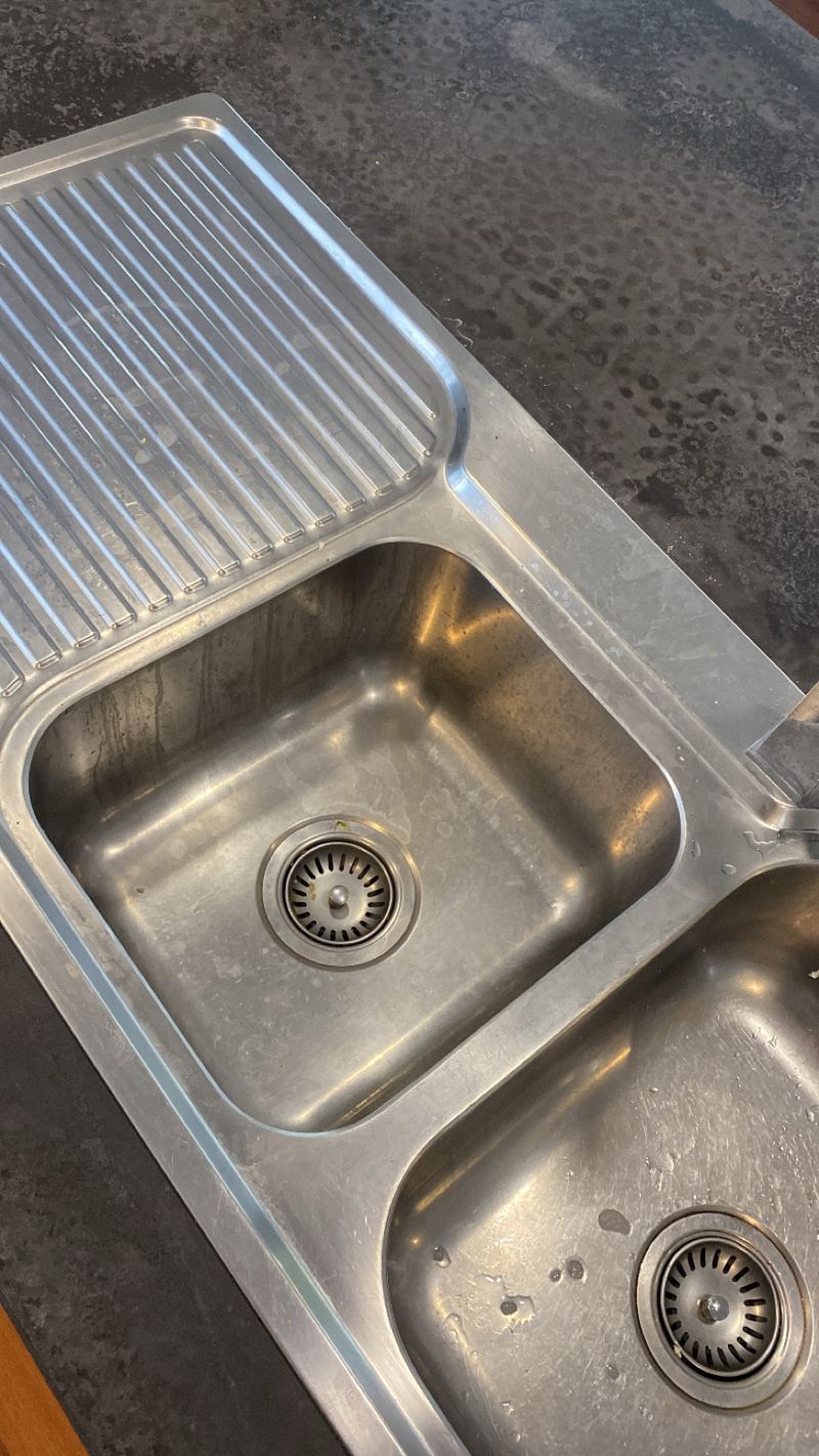 Stainless steel kitchen sink with water spots and dull marks before cleaning